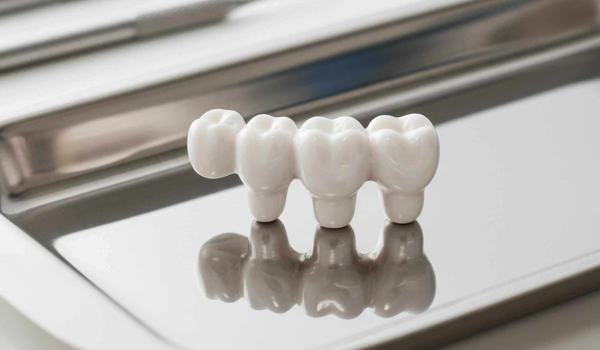 Dental bridge model on a reflective surface, showcasing custom design for tooth replacement at M.Y. Family Dentistry in West Chester, PA.