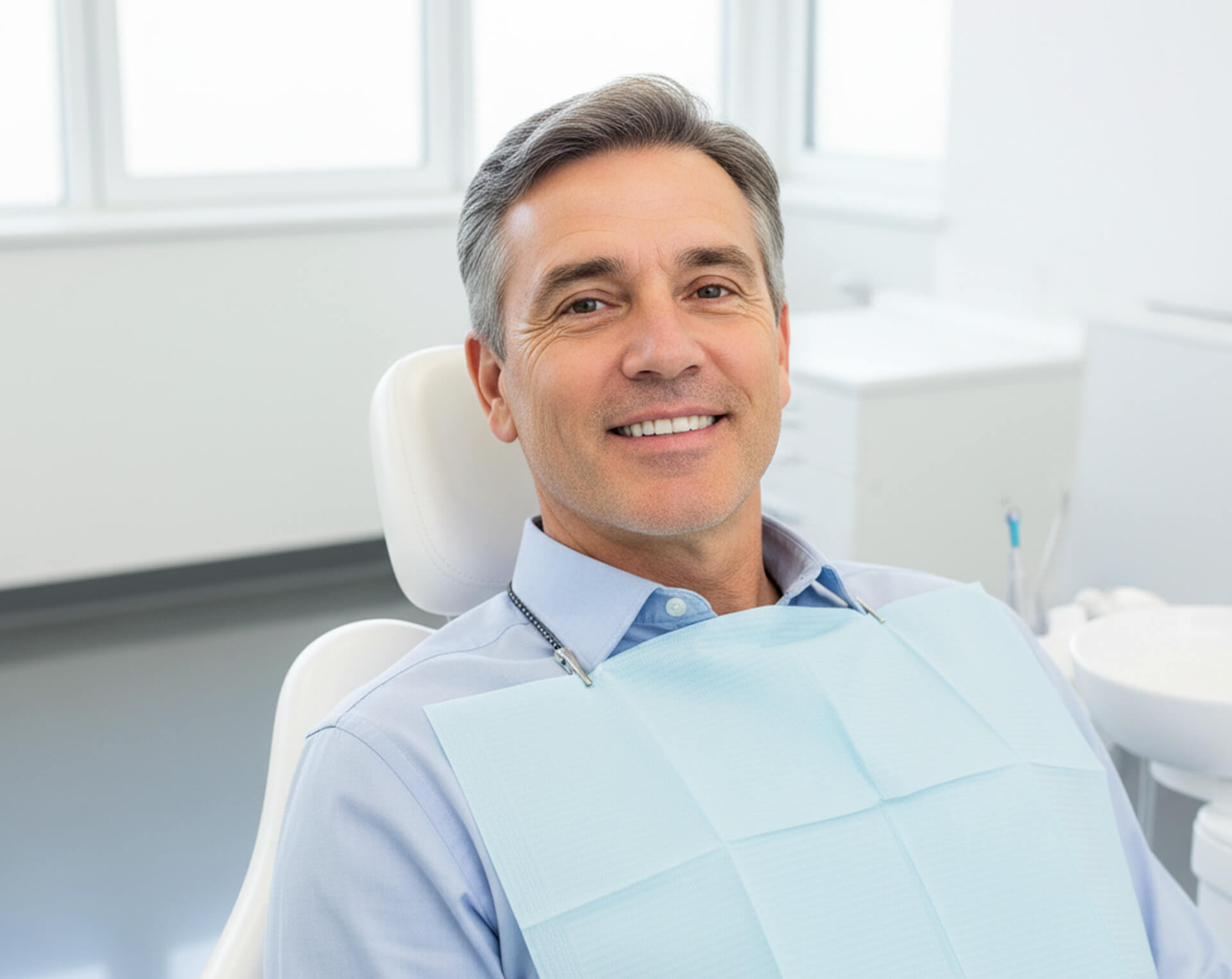 Smiling man in dental chair wearing a bib, representing patient comfort during ceramic crown procedures at MY Family Dental in West Chester, PA.
