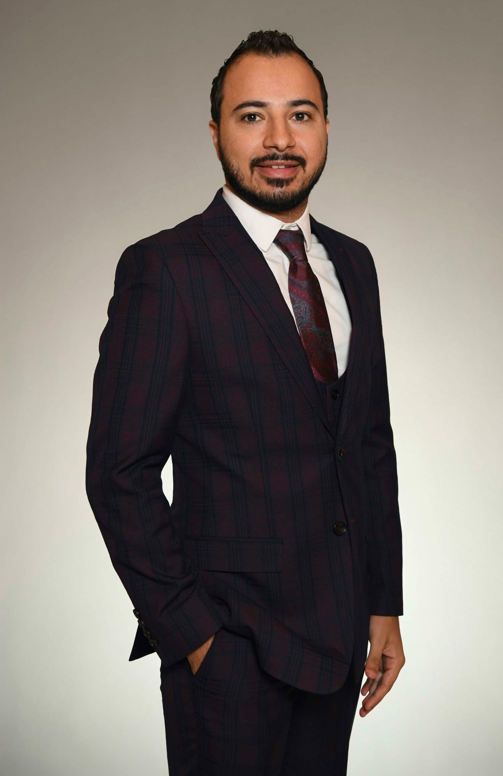 Dr. Mina Yacoub, DMD, FICD, MAGD, in a formal plaid suit, representing M.Y. Family Dentistry in West Chester, PA, emphasizing personalized dental care and advanced techniques.