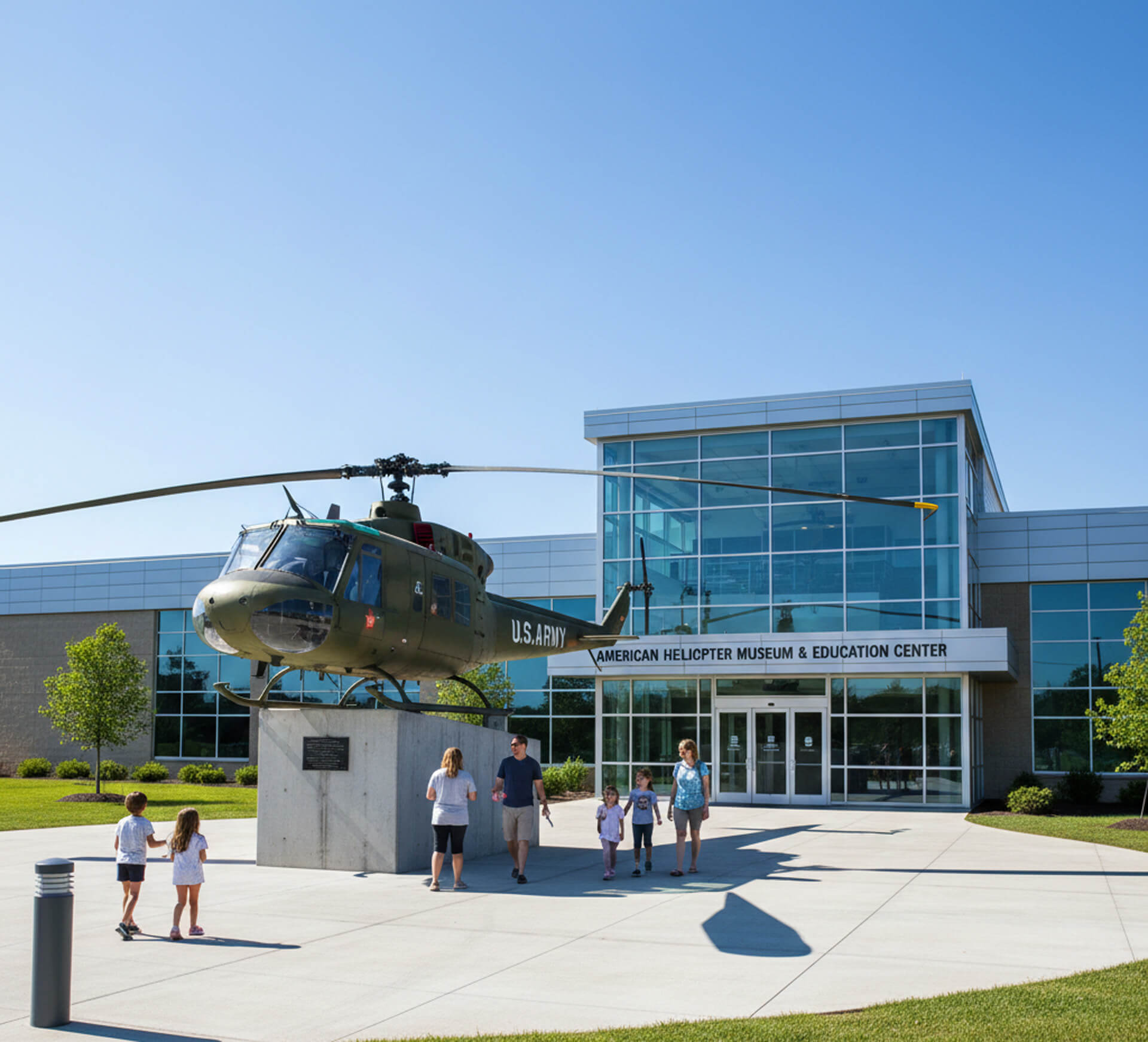 Visitors exploring the American Helicopter Museum & Education Center, featuring a U.S. Army helicopter display in front of a modern building.