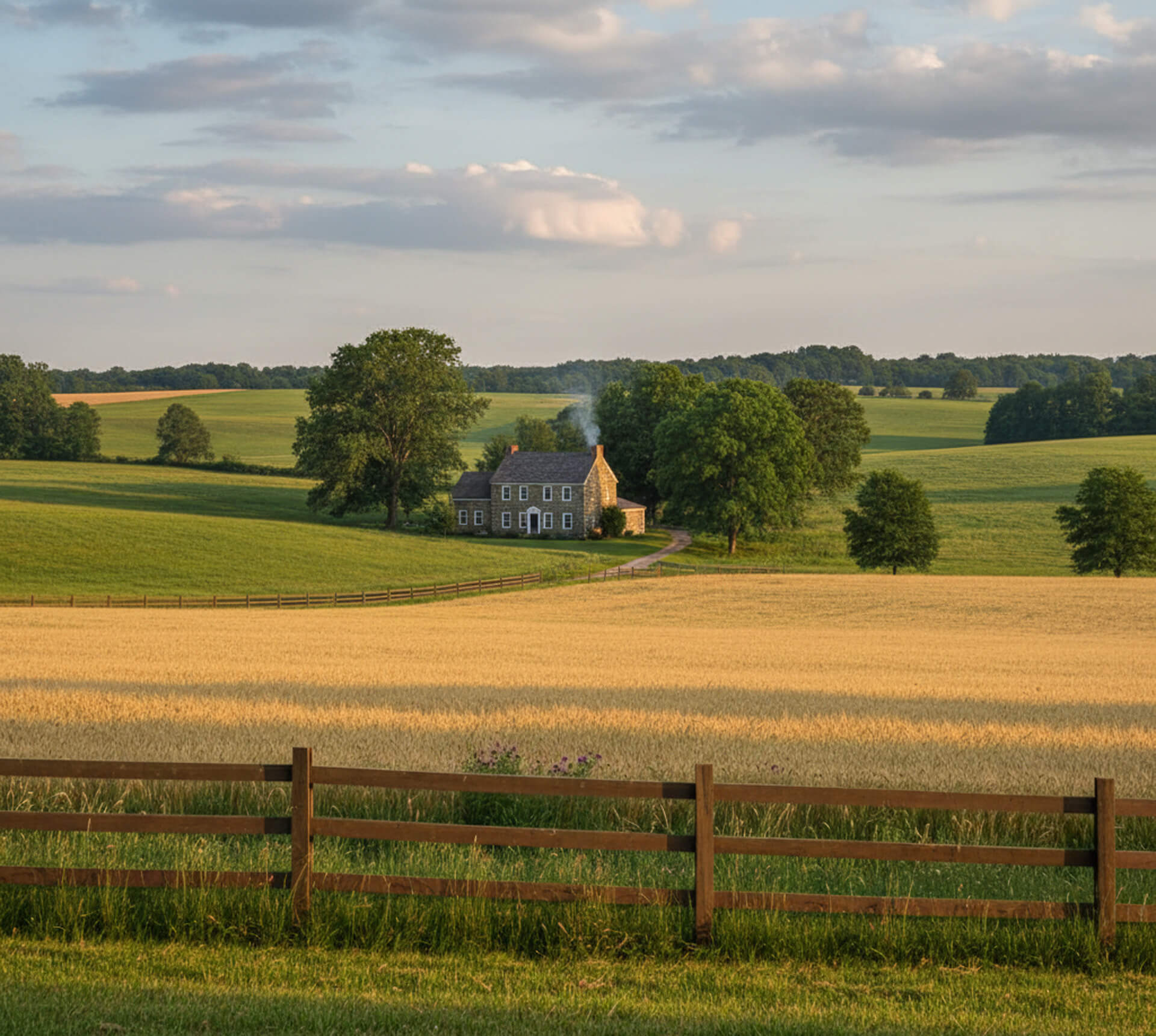 Scenic view of a rural landscape in Frazer, PA, featuring a charming stone house surrounded by green fields and trees, conveying a welcoming atmosphere for families seeking dental care.