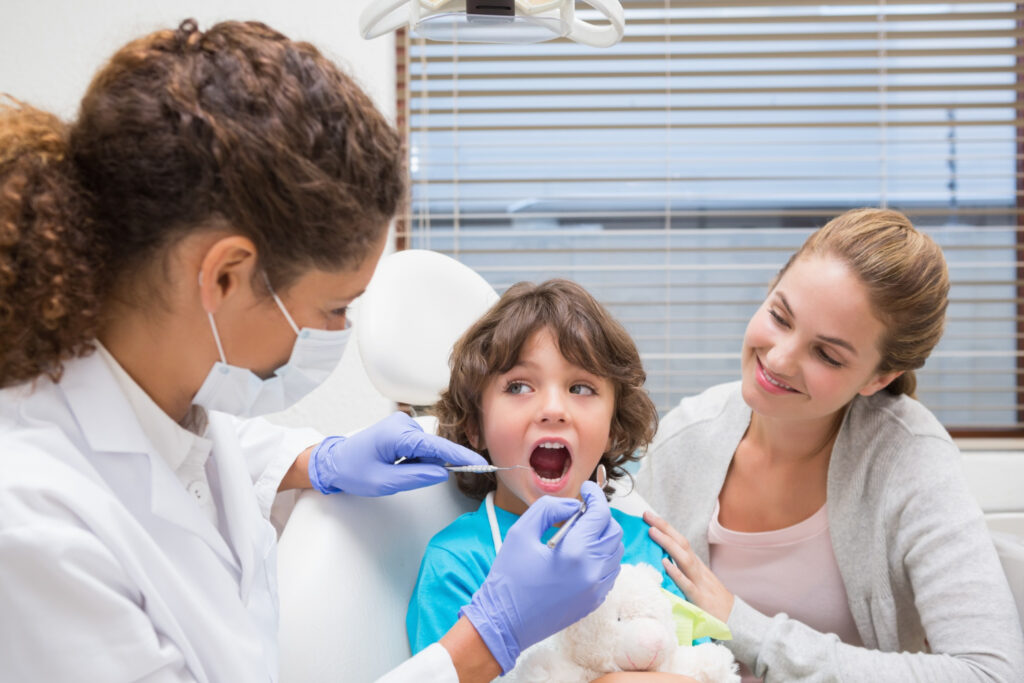 Pediatric dentist performing a gentle dental examination for a child with a parent during a pediatric dental visit in West Chester, PA.