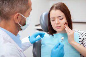 Dentist examining a woman experiencing tooth pain during a dental appointment.