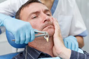 Dentist holding an extracted tooth with dental forceps during a tooth extraction procedure